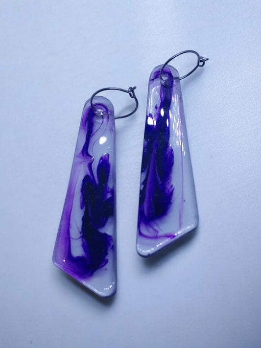 Artymunk3y abstract swirl dangle earrings in purple and indigo on a milky white translucent resin with a glossy finish.
