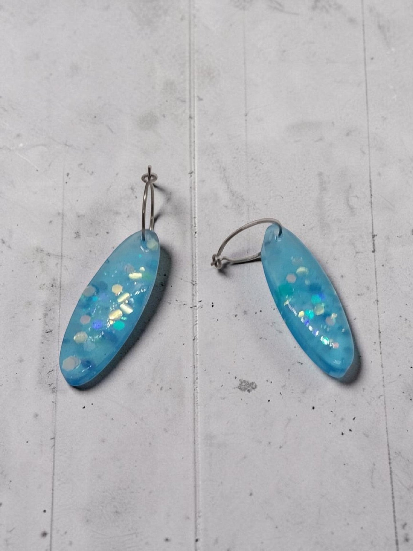 Artymunk3y sky blue oval resin dangle earrings with iridescent glitter and confetti.