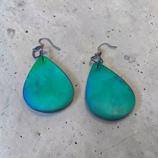 Artymunk3y handcrafted teal and blue gradient teardrop dangle earrings with iridescent metal hooks on concrete.