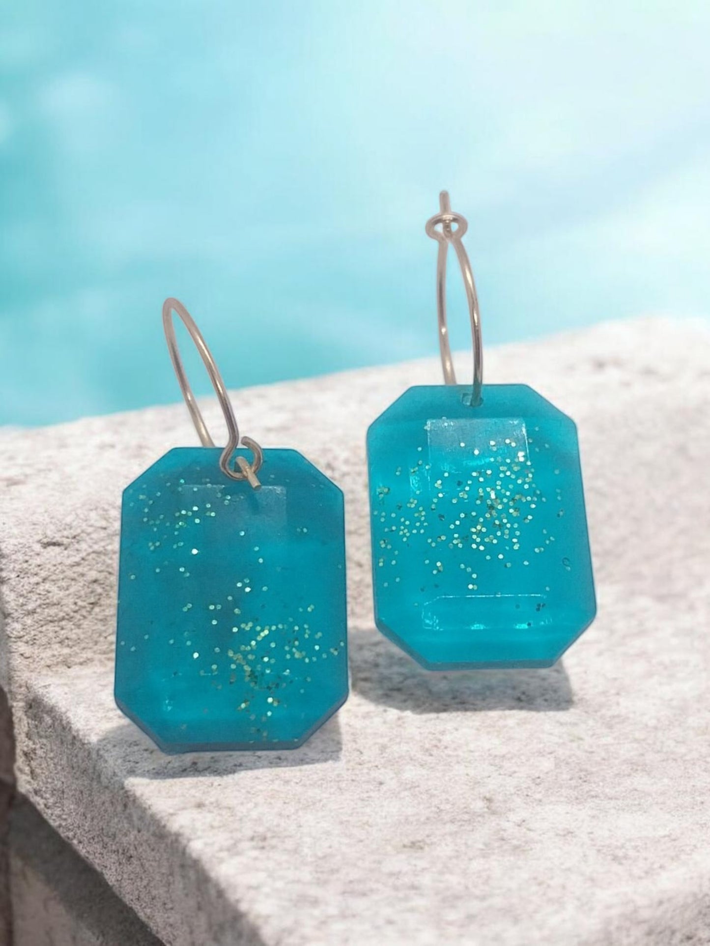 Artymunk3y teal octagonal gemstone hoop earrings with gold glitter accents and gold-tone hoops.