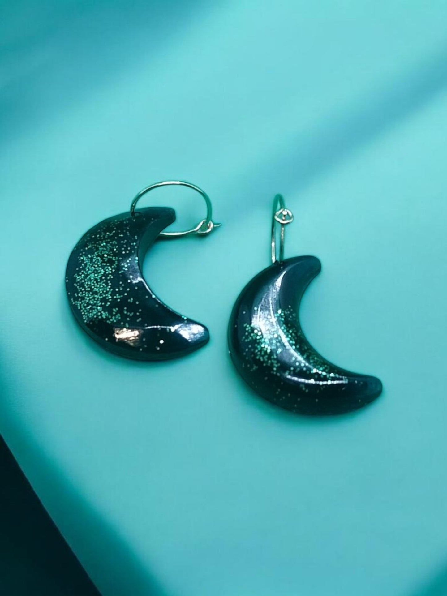 Artymunk3y dark crescent moon dangle earrings with green glitter accents.