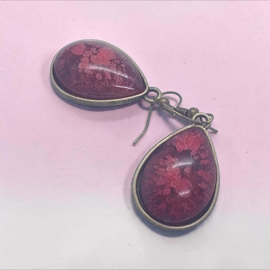Artymunk3y teardrop dangle earrings featuring deep crimson resin with floral patterns in antique-bronze settings.