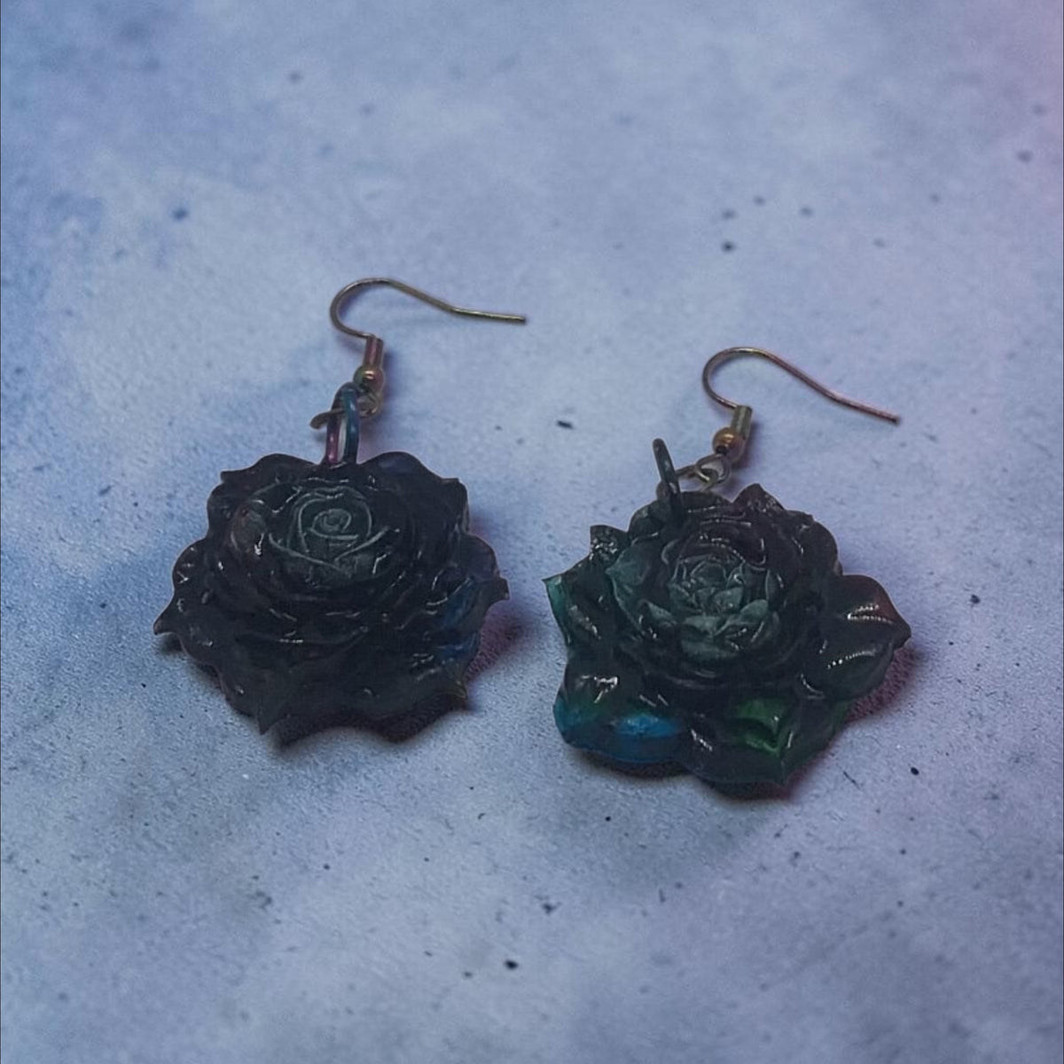 Artymunk3y handcrafted dark floral rose drop earrings with moody blue and green iridescent petals on hook fastenings.