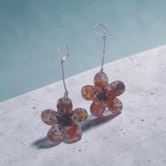 Artymunk3y floral drop earrings featuring clear resin flower pendants with amber, orange, and red confetti accents.