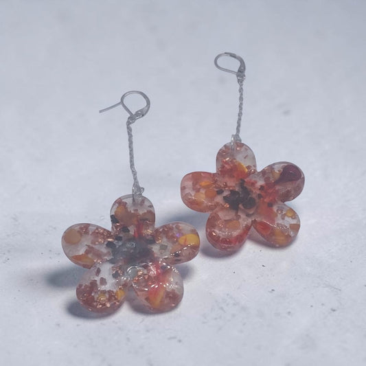 Artymunk3y floral drop earrings featuring clear resin flower pendants with amber, orange, and red confetti accents.
