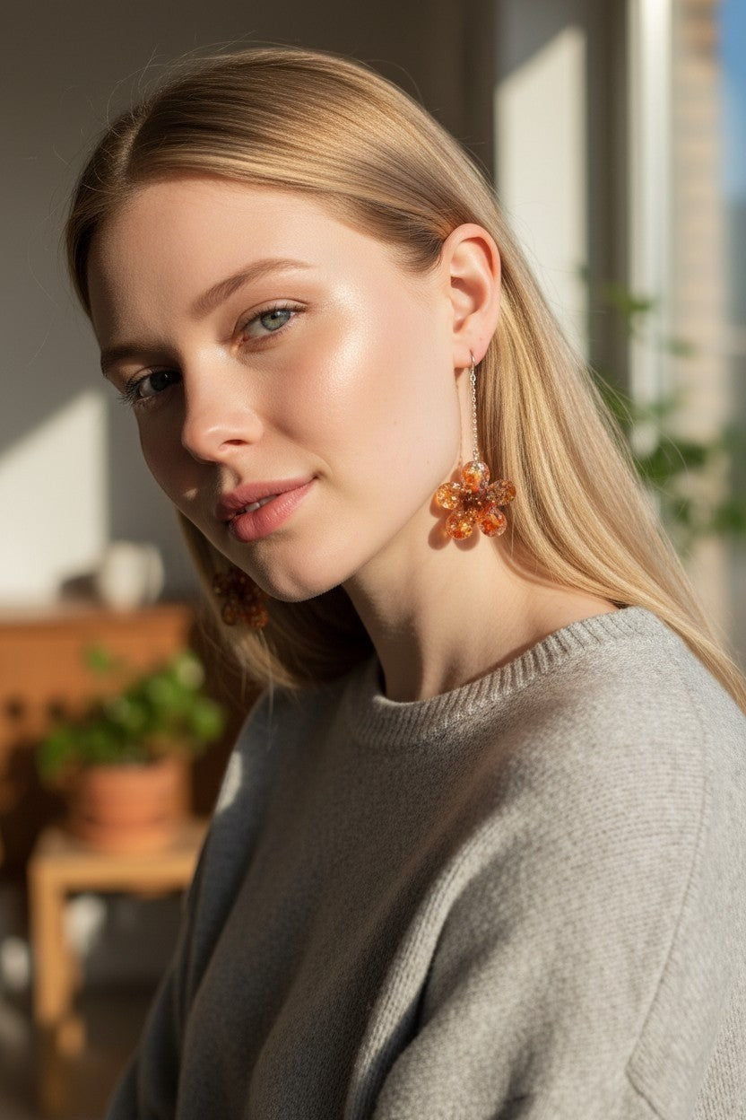 Artymunk3y floral drop earrings with amber resin flower pendants and silver chains worn by a blonde woman