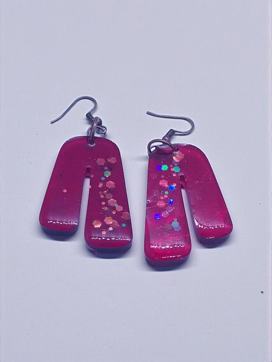 Artymunk3y fuchsia arch shaped resin earrings with iridescent glitter accents.