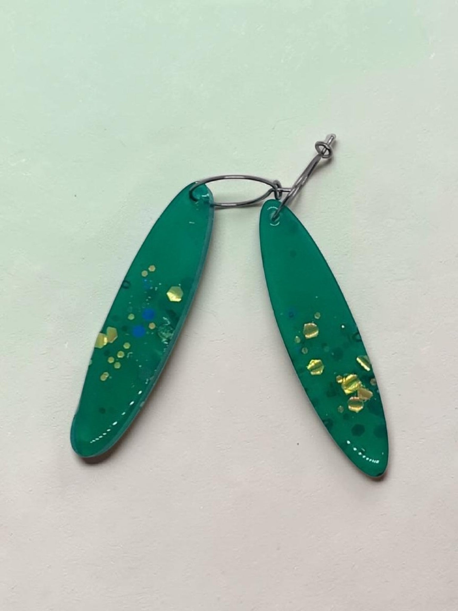 Artymunk3y green resin teardrop earrings with gold, yellow, and blue glitter accents.