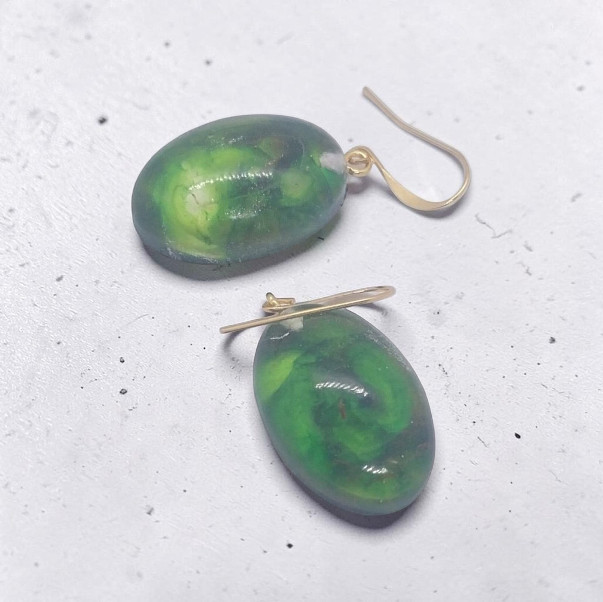 Artymunk3y oval drop earrings featuring green resin pendants with emerald swirls and gold-toned hook wires.
