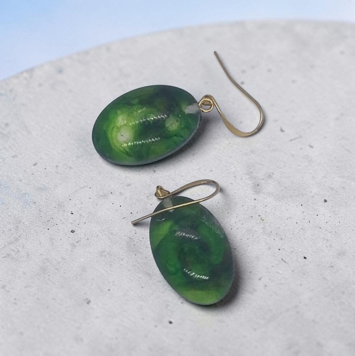 Artymunk3y oval drop earrings featuring green resin pendants with swirling patterns on gold-toned hook wires.