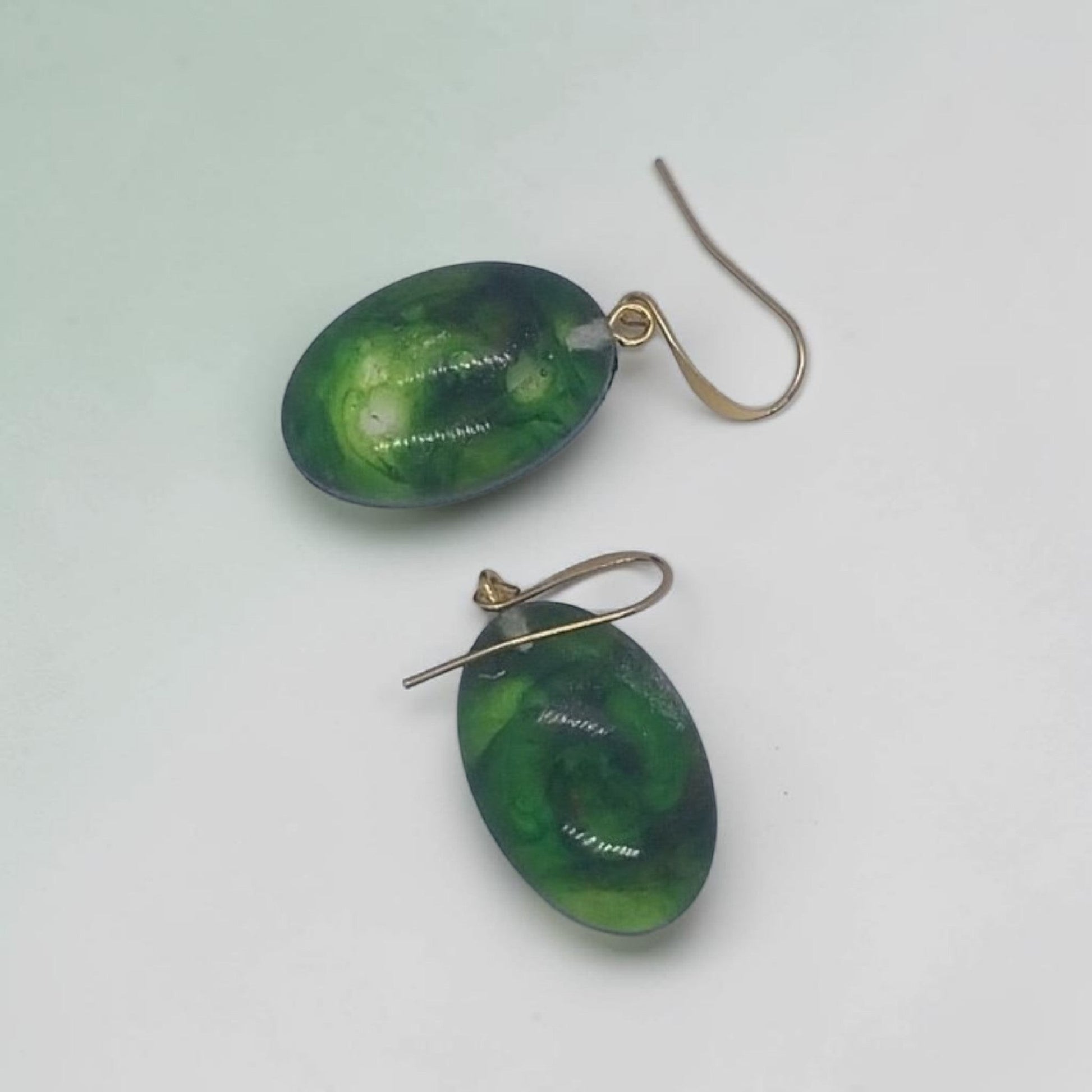 Artymunk3y oval drop earrings featuring green resin pendants with swirling patterns and gold-toned hook wires.