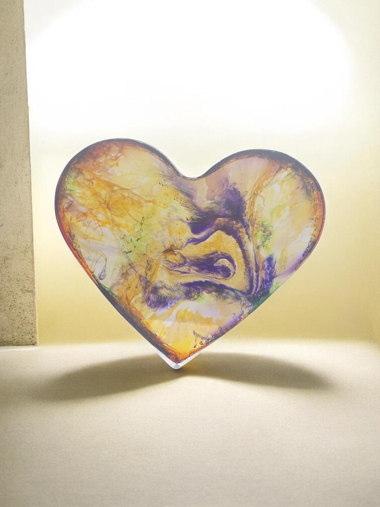 Artymunk3y heart-shaped resin display with abstract swirls of yellow, orange, purple, and green.