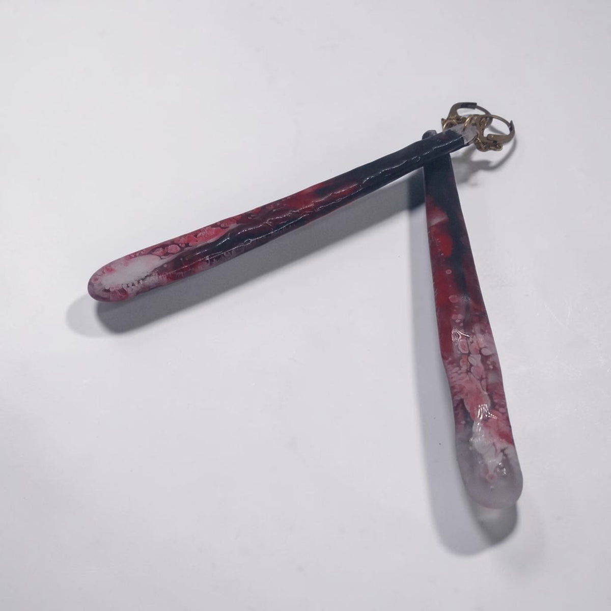 Artymunk3y long drop earrings featuring marbled black, crimson, and white resin with gold-toned hardware.