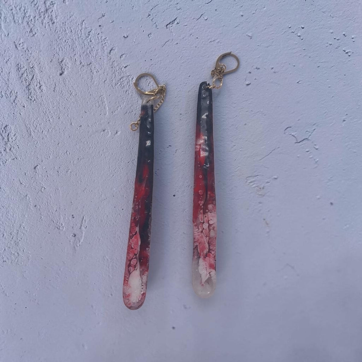 Artymunk3y long resin drop earrings featuring marbled black, crimson, and white swirls with gold-toned hardware.