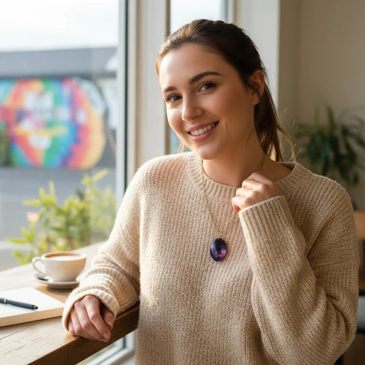 A woman wearing an Artymunk3y oval purple resin pendant necklace with a gold chain, styled with a beige sweater.