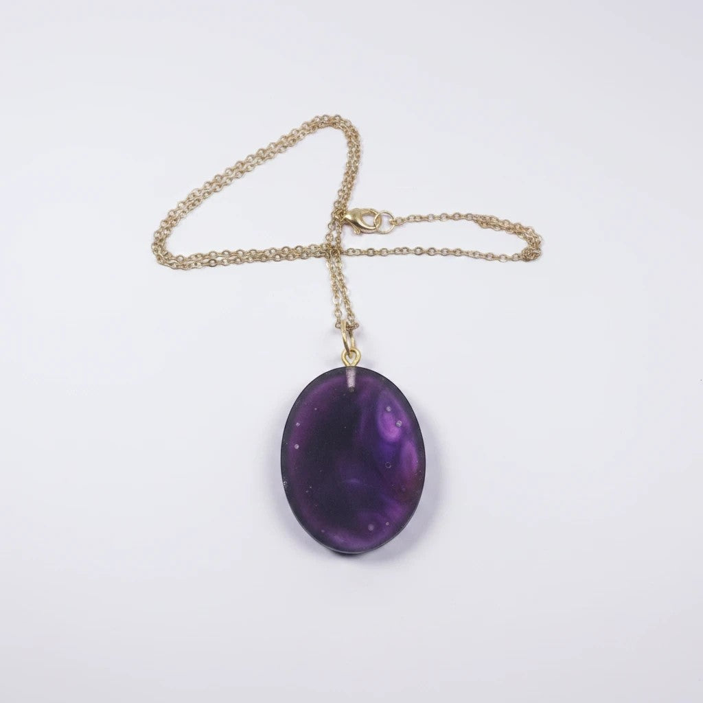 Artymunk3y oval pendant necklace featuring a purple galaxy-style resin stone on a delicate gold-toned chain.