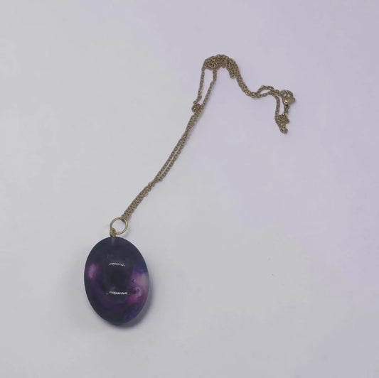 Artymunk3y oval pendant necklace featuring a purple galaxy-swirl resin stone on a delicate gold-toned chain.