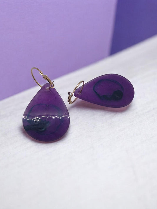 Artymunk3y teardrop resin dangle earrings in translucent purple with blue and black swirls, gold-toned leverback closures.