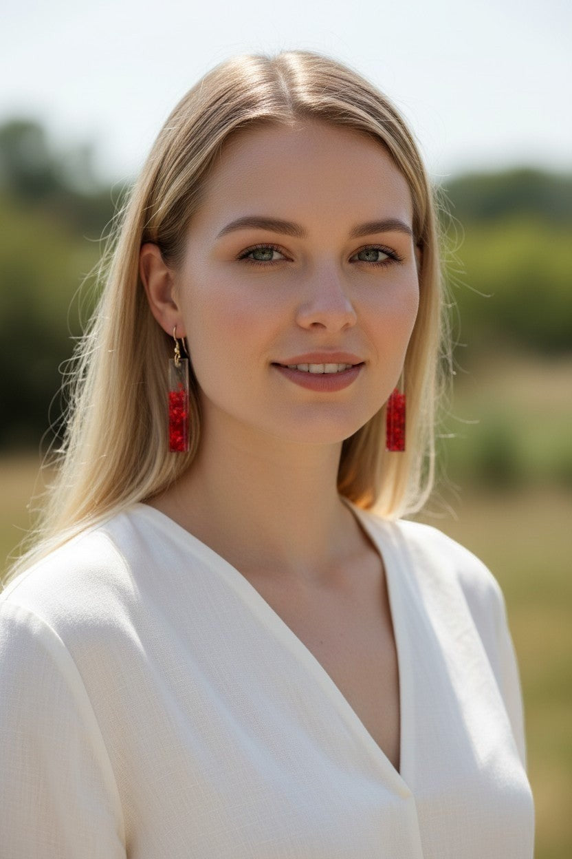 Artymunk3y rectangular resin drop earrings with red accents and gold-tone hoops worn by a woman outdoors
