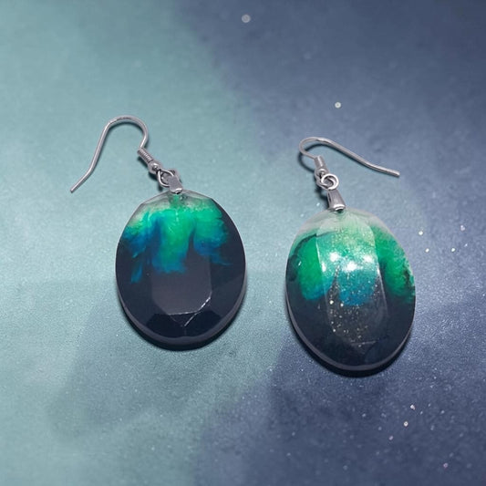 Artymunk3y handcrafted resin oval drop earrings with swirling emerald green, teal, and black nebula patterns.