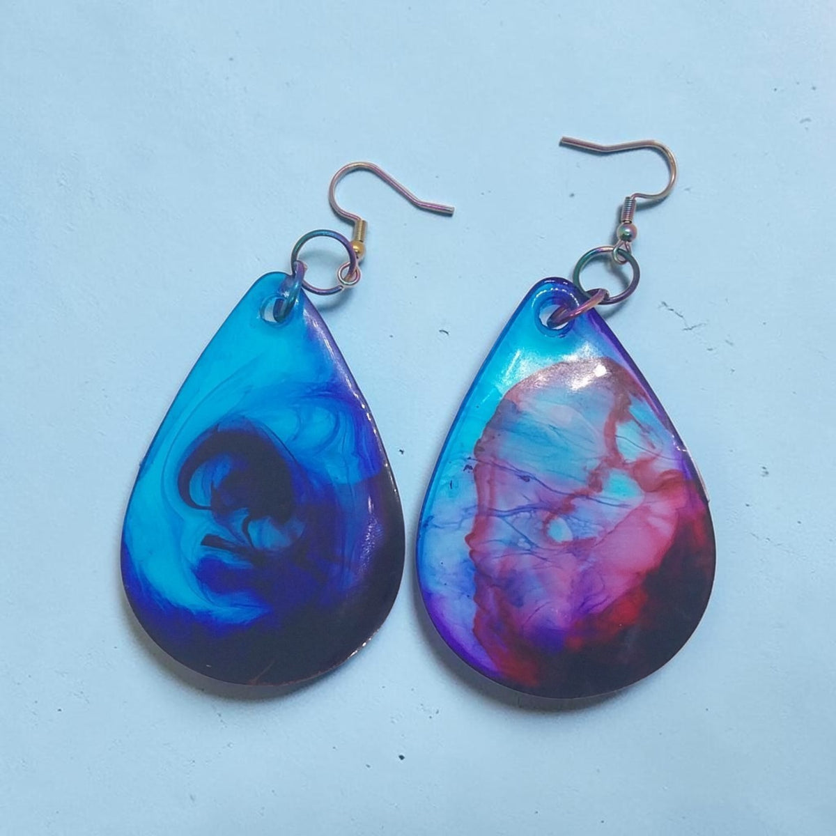 Artymunk3y handcrafted resin teardrop dangle earrings with a galaxy-like swirl of blue, purple, and pink colours.