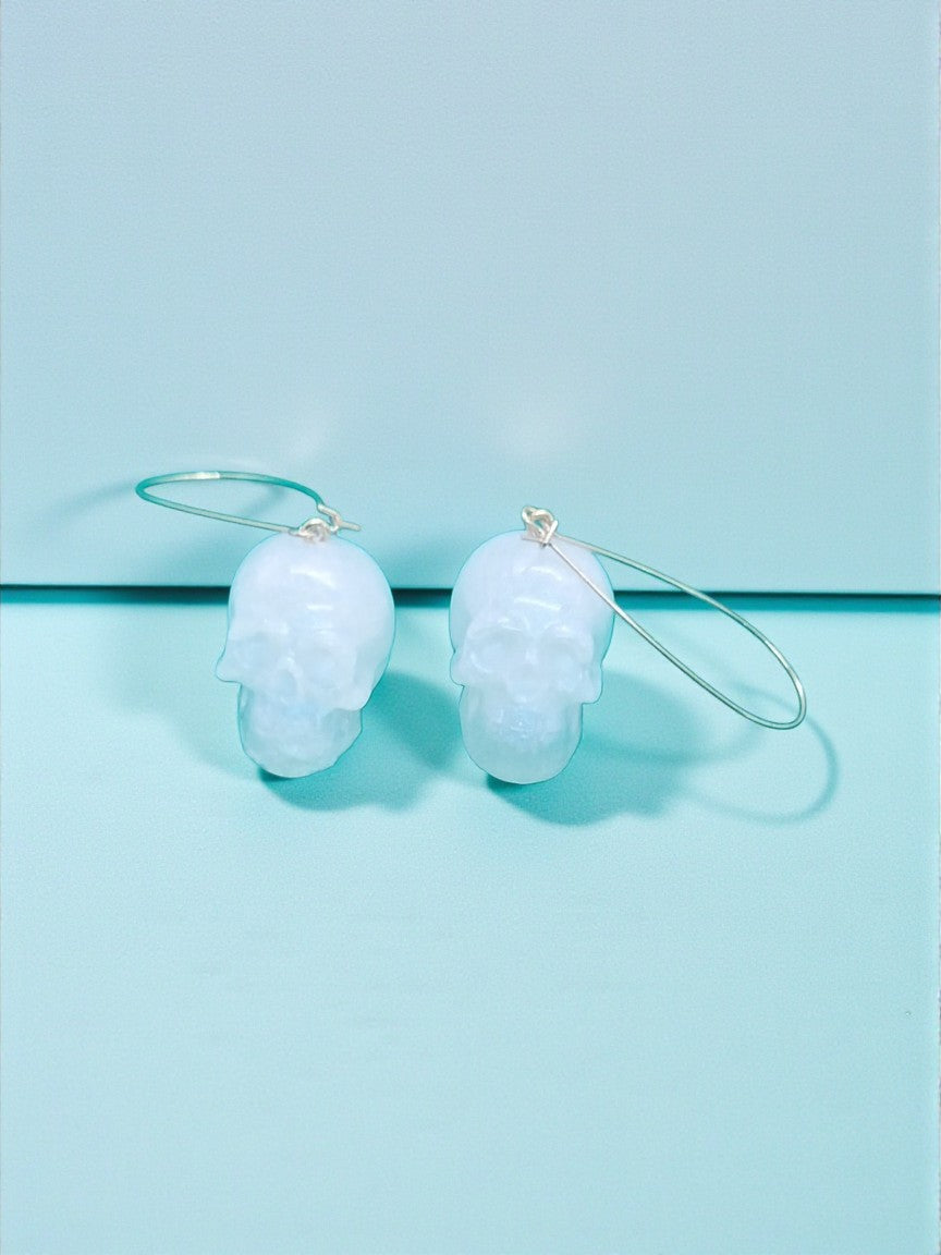 Artymunk3y pale blue translucent skull shaped dangling earrings with minimalist hoops.