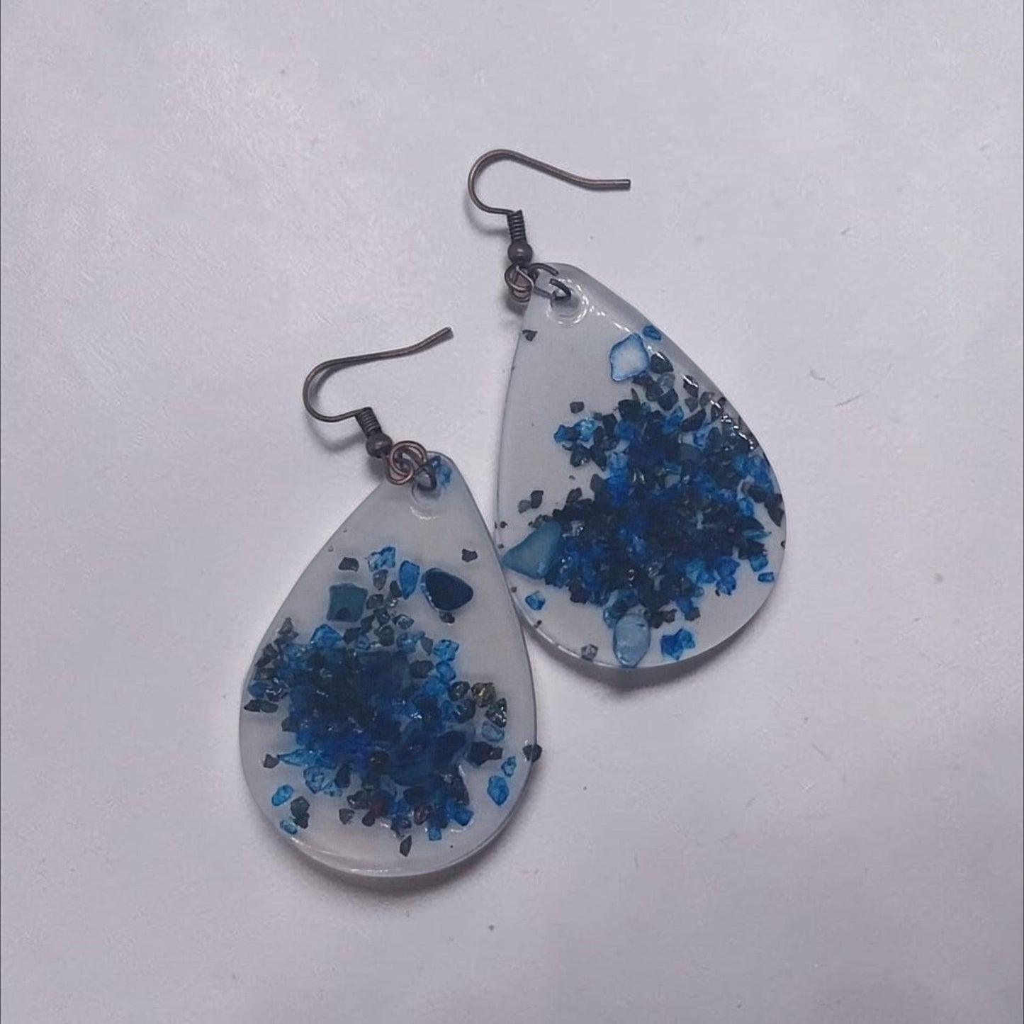 Artymunk3y teardrop resin dangle earrings with deep blue crushed stone accents and rustic metal hooks.