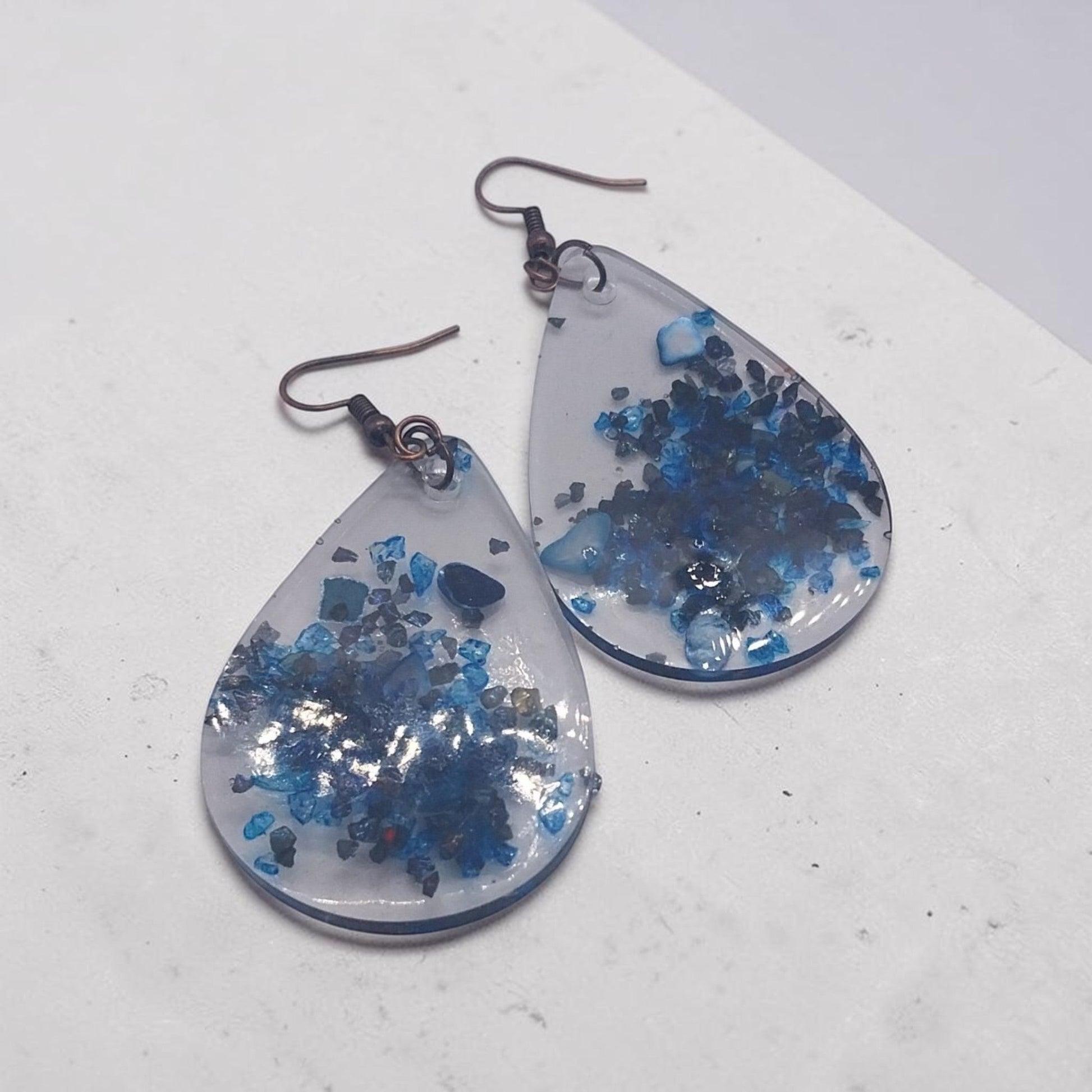 Artymunk3y teardrop resin dangle earrings with deep blue crushed stone accents and rustic metal hooks.