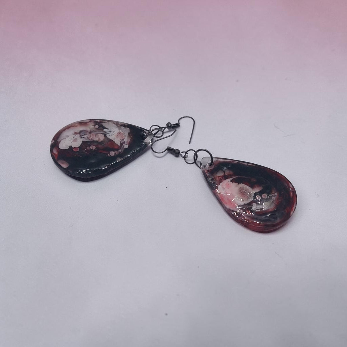 Artymunk3y handcrafted teardrop resin earrings with a black, crimson, and white marble swirl pattern.
